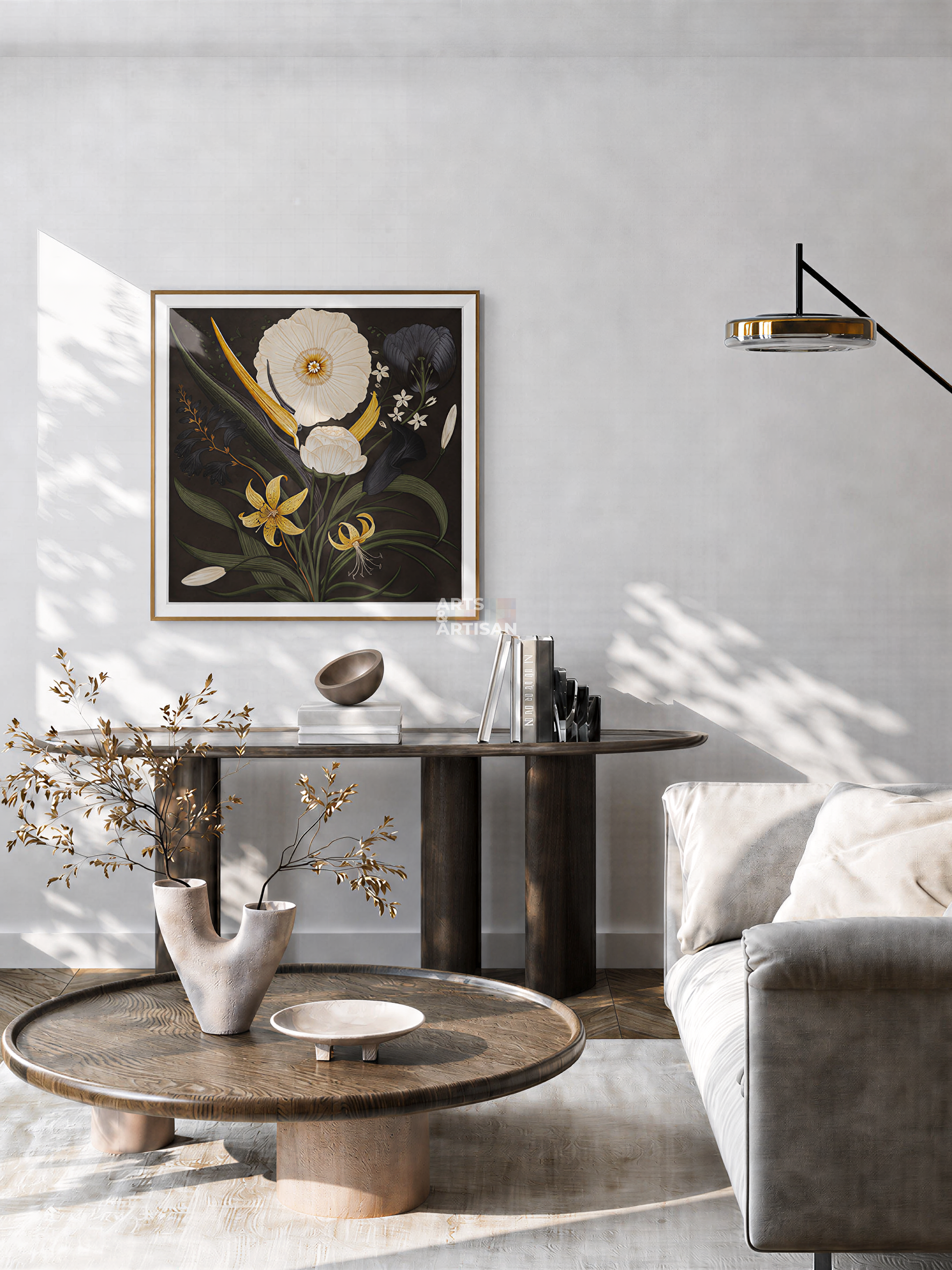 A framed Hermes Scarf 80 with white, yellow, and green botanical elements on a dark background, displayed on a light gray wall in a modern living room setting above a dark console table.