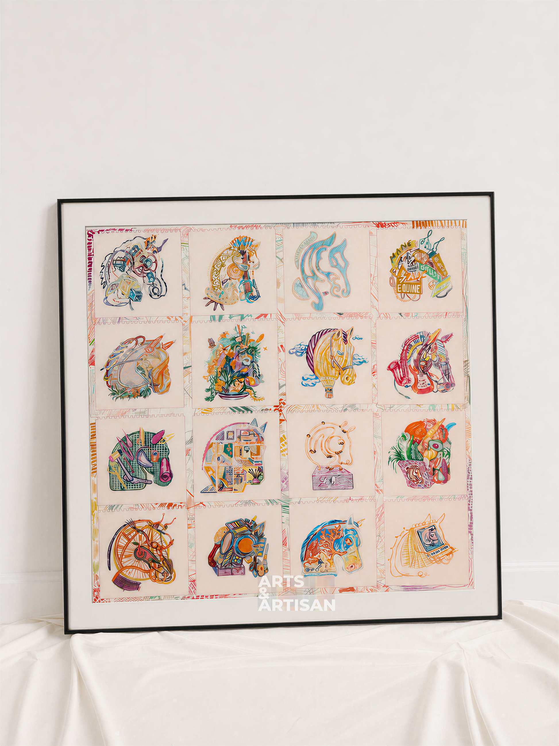A framed Hermes Scarf 80 featuring a 4x4 grid of colorful unicorn illustrations on a light pink background, leaning against a white wall on draped white fabric.